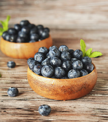 fresh bilberries or blueberries in small wooden bowls, selective focus
