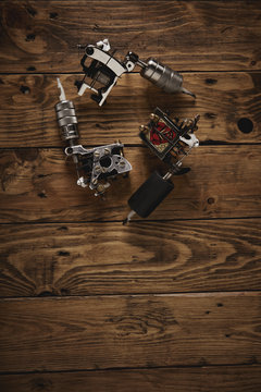 Three different custom hand made electric traditional professional tattoo guns arranged on a brown wooden table