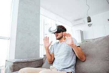 Shocked young man wearing virtual reality device
