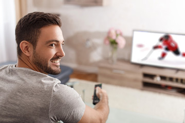 Excited man switch TV to ice-hockey