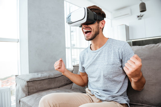 Happy man making winner gesture while wearing virtual reality device