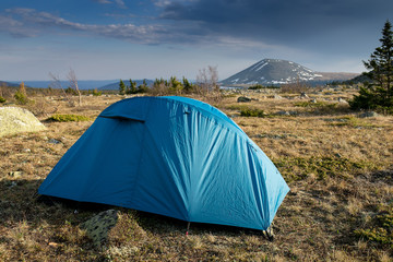 Camping tent near high moutain in the evening sunset time, Ural, Russia