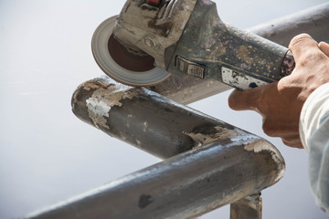 worker cuts a metal pipe with some electric device or appliance