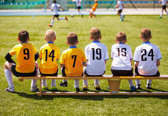 Young Football Players. Young Soccer Team Sitting on Wooden Bench. Soccer Match For Children. Young...
