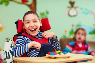 cheerful boy with disability at rehabilitation center for kids with special needs - obrazy, fototapety, plakaty