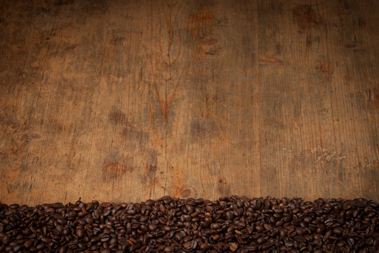 Coffee beans on a wooden table shot form above with room for copy