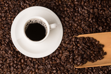 coffee cup on a bed of beans and a serving spoon  shot from abov