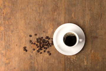 coffee cup on wooden surface, topview with some beans and room for copy