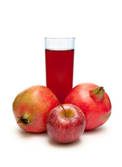 pomegranate, red apple and a glass of juice on a white backgroun