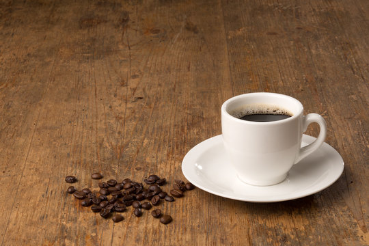 coffee cup with beans on wooden surface with copyspace