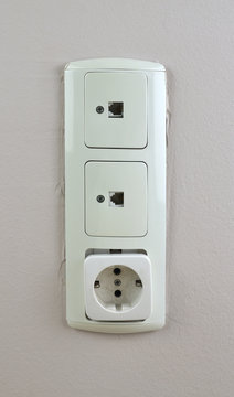Three old used sockets on a wall- two for network cable and one for electric plug