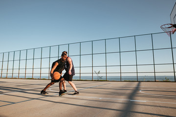 Portrait of a two sportsmen playing basketball at the playground