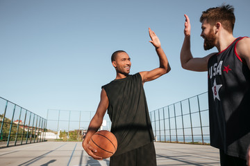 Sportsmen giving high five while playing basketball at the playground