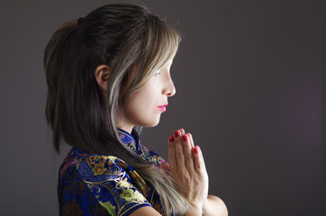 Samurai woman dressed in traditional colorful flower pattern asian silk dress, holding hands together as in praying, seen from profile angle, ninja concept