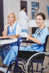 Obraz premium Portrait of smiling doctor sitting on wheelchair with colleagues