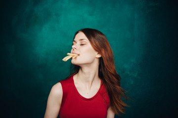 Pretty women eating a lot of potatoes fries. Happiness from food. 