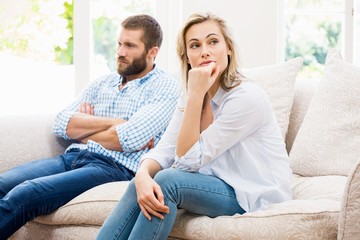 Young couple ignoring each other in living room - obrazy, fototapety, plakaty