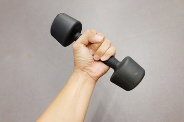 Hands holding dumbbells in sport club or gym and fitness room.