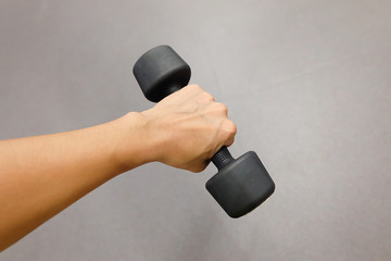 Hands holding dumbbells in sport club or gym and fitness room.