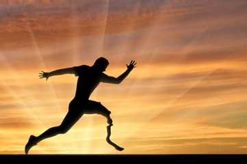 Fototapeta na wymiar Paralympic runner with prosthesis crossing finish line sunset
