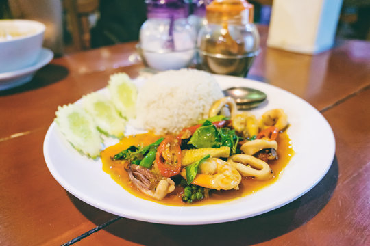 Thai cuisine, rice and spicy sauce with seafood, water spinach and pods fresh hot pepper. This national dish in Thai cafe is typical for Thailand. Shallow depth of field.