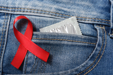Red ribbon and condom on jeans - HIV awareness 