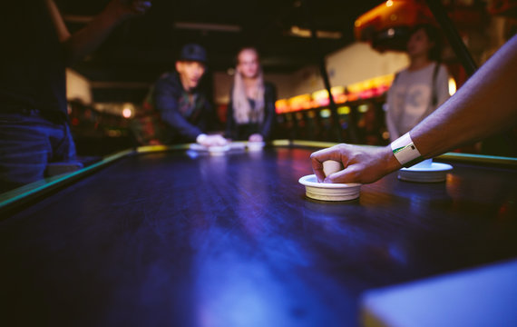 Young friends playing air hockey game