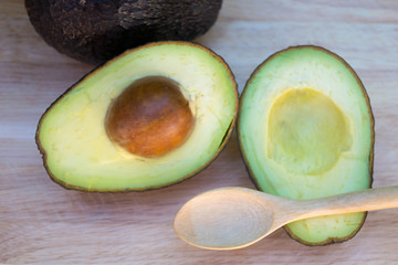 Avocado and avocado pieces on a wooden floor and has a background of green tree, Selected focus