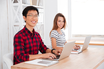 Emotional students working on their laptops in a classroom