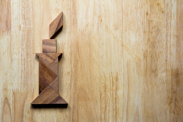 Wooden tangram puzzle in candle with flame shape