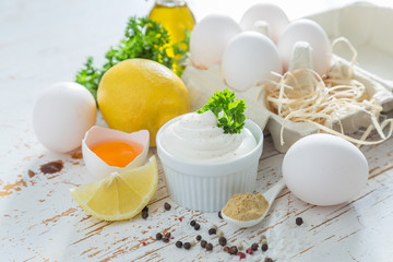 Mayonnaise sauce and ingredients on wood background