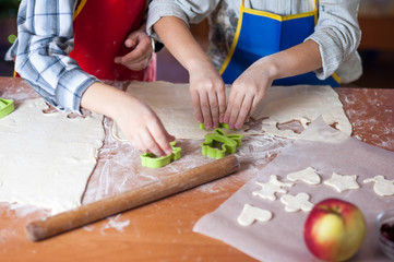 hands of a child who is preparing cookies in the kitchen with flour and dough