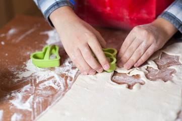 hands of a child who is preparing cookies in the kitchen with flour and dough