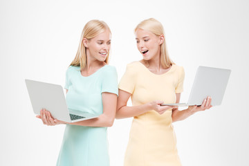 Two happy young women looking at their laptops