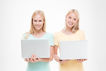 Young happy women looking at the camera and holding laptops