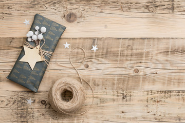 Fototapeta na wymiar Top view on nice Christmas gifts packed in black and striped paper and decorated with stars on wooden background. Presents and decor elements. Holidays and winter concept.