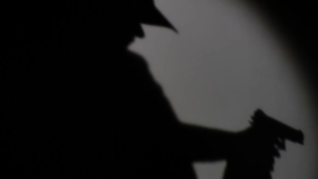 silhouette of an armed person with a cap sneaking through a room