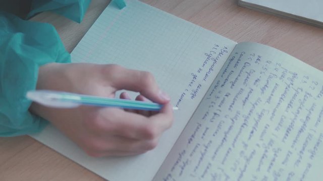 Close-up of a school notebook in the box. Schoolboy wrote in a notebook with a ballpoint pen with blue ink. School lesson. Russian language: Russian letters written