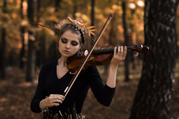 Fototapeta premium Young woman fiddle violin over the fall park background