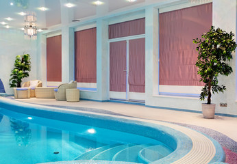 Relaxation zone near blue mosaic swimming pool with furniture