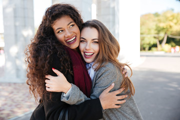 Happy meeting of two friends hugging with street on background