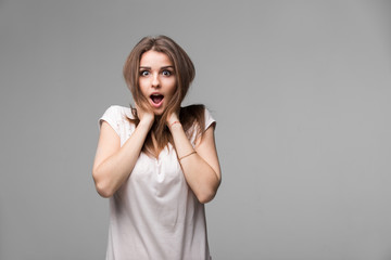 Portrait of beautiful brunette woman with a astonished expression posing in studio on gray...