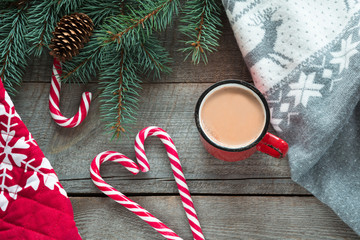 Christmas drink. Mug hot coffee with milk, red candy cane on the wooden background. New Year. Holiday card. Rustic style. Top view and copy space.
