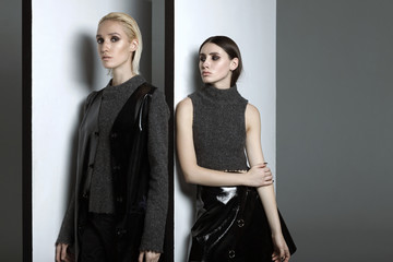 Fashion photography. Girls in black and gray dress in designer studio on a gray background. Girl blonde in raslablennoy pose. The girl brunette posing. Advertising clothes