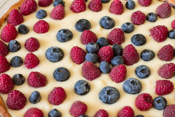 Tart with custard, blueberries and raspberries in glass brazier. Closeup.