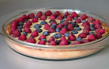 Tart with custard, blueberries and raspberries in glass brazier. Closeup.