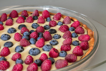 Tart with custard, blueberries and raspberries in glass brazier. Closeup.