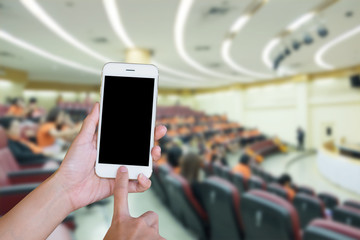 Hands woman holding touch screen smart phone,tablet on blurred .audience at the conference hall background.