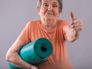 Elderly woman with yoga mat
