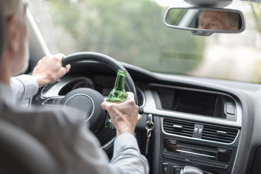 Man holding an beer bottle and driving